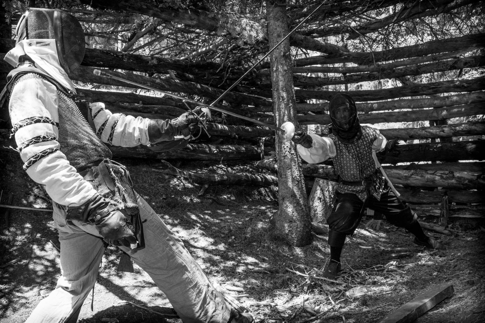 Two people fencing in a wood structure